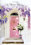 A welcoming front door scene unfolds as if along one of Hither Green's leafy residential streets, where flowers spill over garden walls in spring. The door itself is painted a soothing, pastel pink, its panels subtly catching the light and giving the entrance a gentle, almost storybook charm. Surrounding this doorway, whitewashed walls and a softly painted shutter provide a clean, calm backdrop, allowing the eye to linger on the abundance of wisteria that cascades above. The wisteria blooms in generous swathes of lavender and soft purple, clusters hanging down like fragrant garlands that frame the door and filter sunlight into delicate, shifting patterns of light and shade. At the foot of the steps, a florist's grey tin bucket is carefully positioned, brimming with white and creamy roses. The roses are full and plush, their petals layered and velvety, interwoven with sprigs of fresh green foliage that offer contrast and a sense of natural ease. Around the bucket's base, a pink ribbon is tied in a graceful knot, its colour harmonising with the door and linking every element together in a pastel symphony. The whole scene feels imbued with quiet optimism, as if someone has just had their new keys pressed into their hand and this arrangement has been left as a tender surprise. It evokes the thrill of settling near Manor House Gardens or close to Hither Green station, and would sit beautifully on a new home card or as inspiration for a same-day housewarming delivery that whispers, you're exactly where you're meant to be.